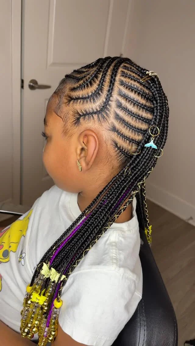 Person with braided hair styled in cornrows, wearing a white shirt with yellow accents.