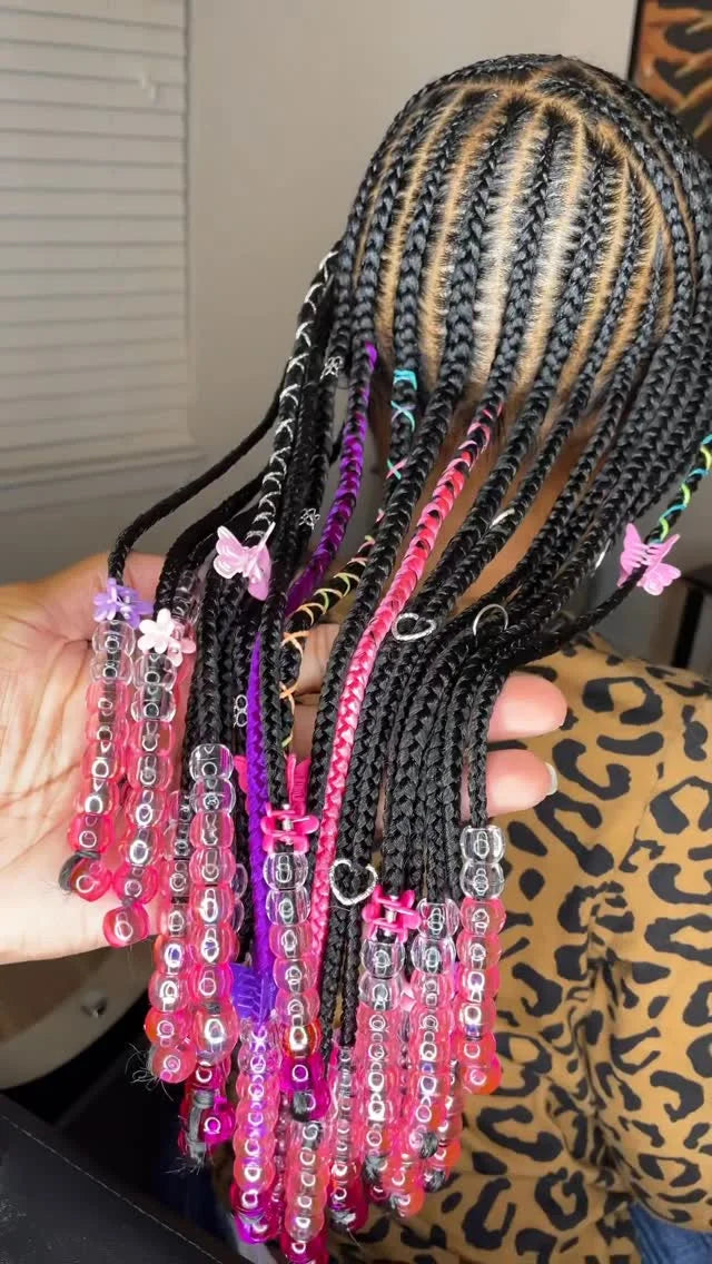 Collection of braided hair extensions with colorful beads held by a person.