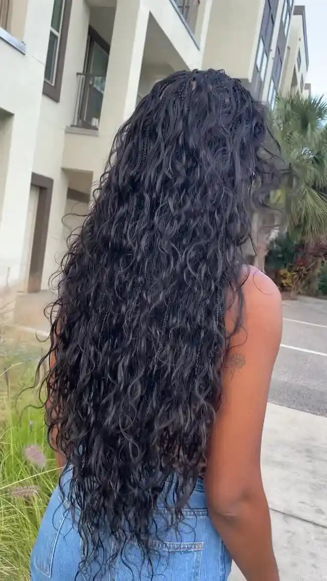 Person with long, curly black hair standing outdoors near a building.