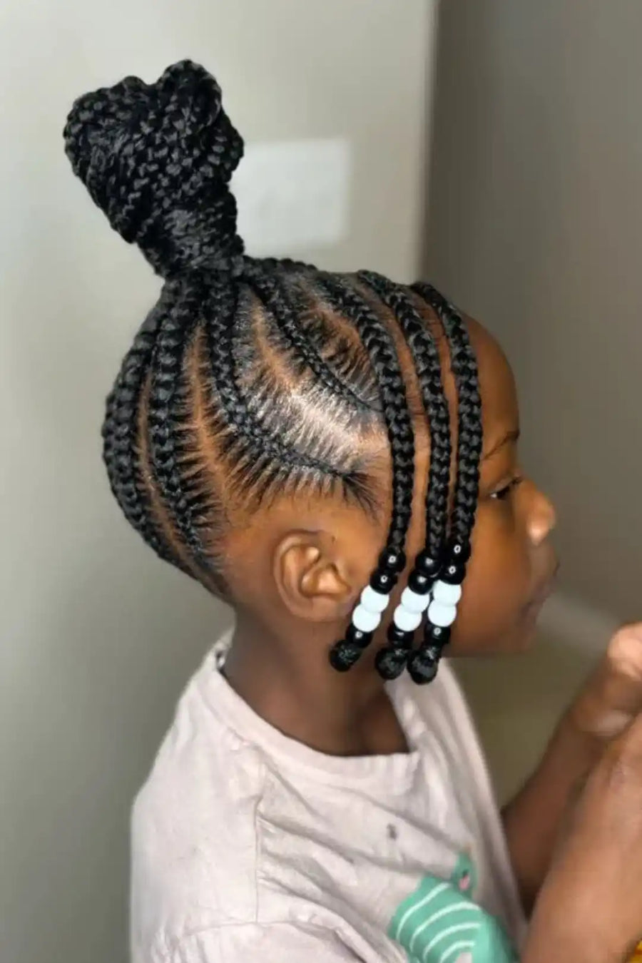 Child with braided hair styled in cornrows against a neutral background
