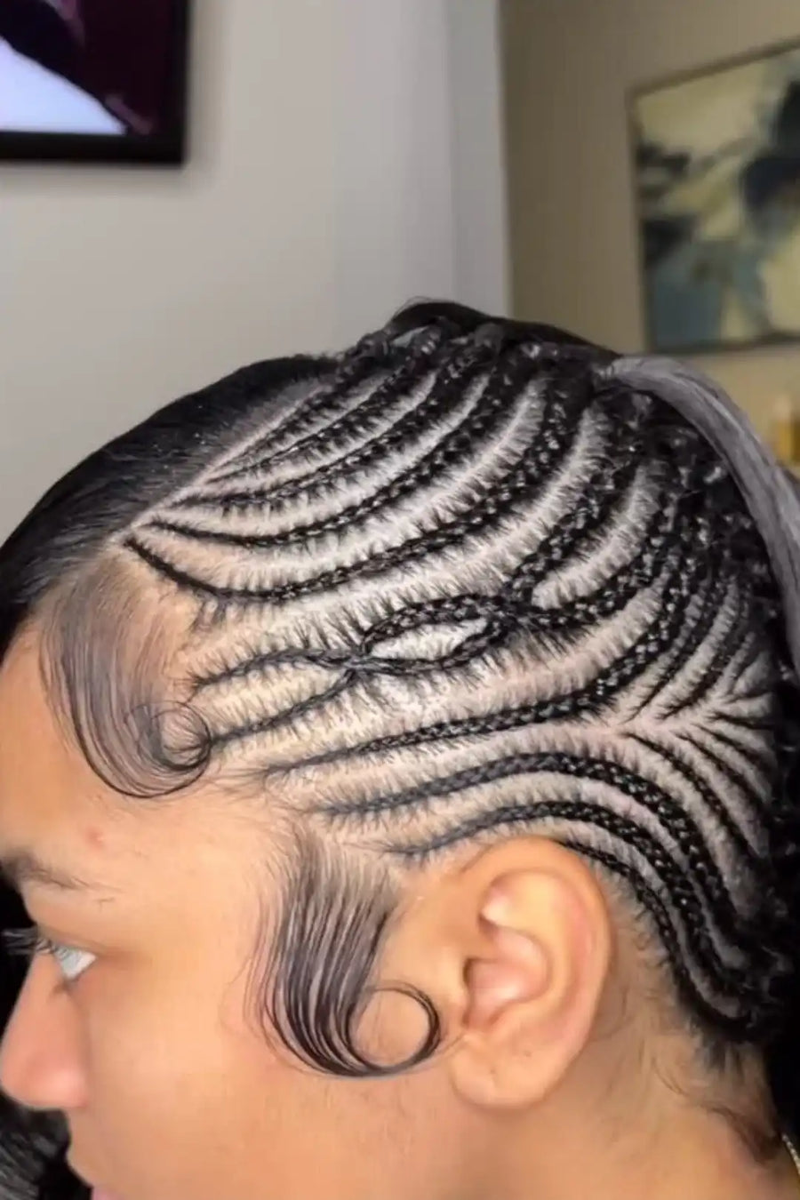 Person with intricate braided hairstyle in a room setting