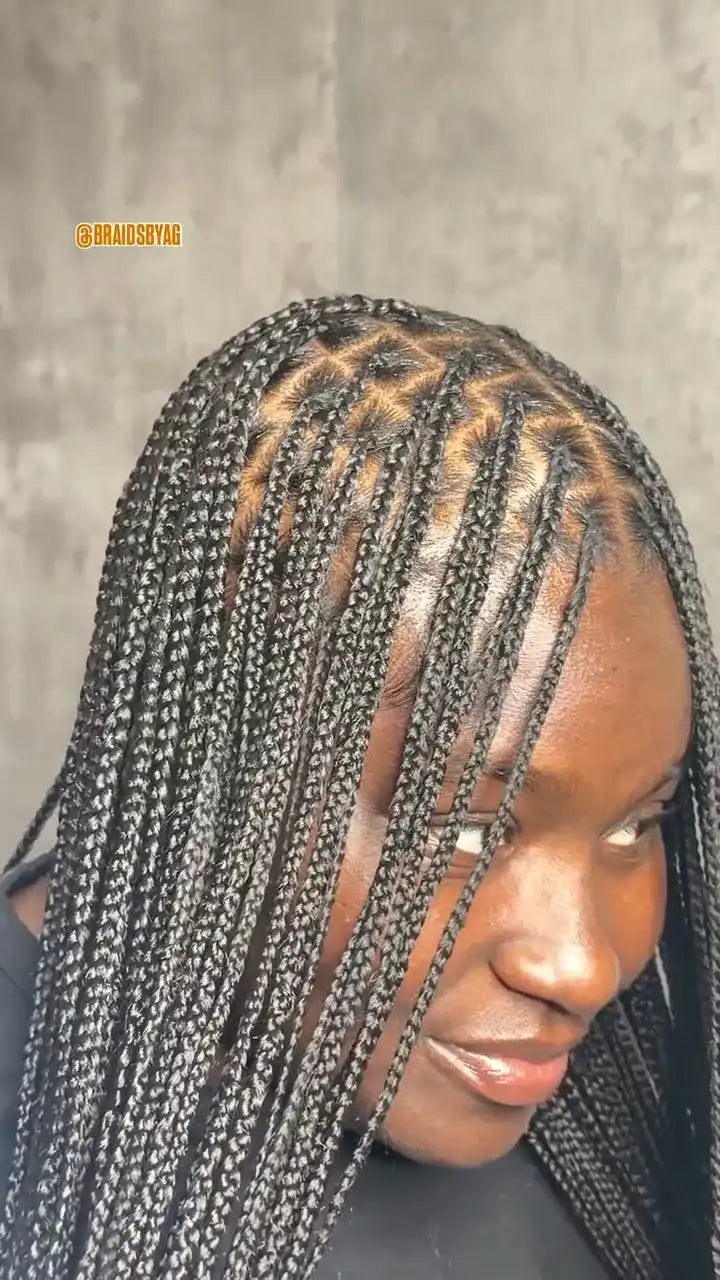 Person with braided hair against a gray background