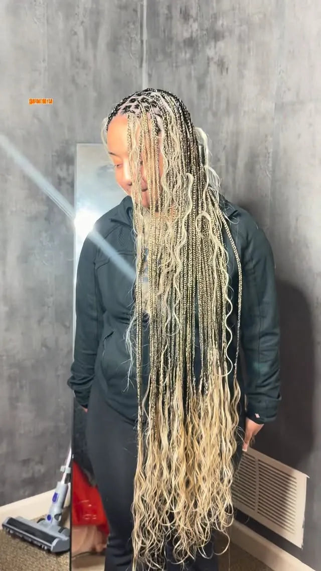 Person with long braided hair standing in front of a mirror.