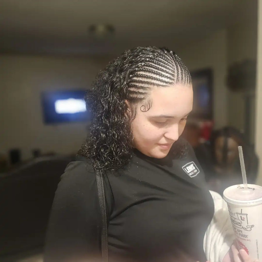 Person with braided hair holding a drink in an indoor setting