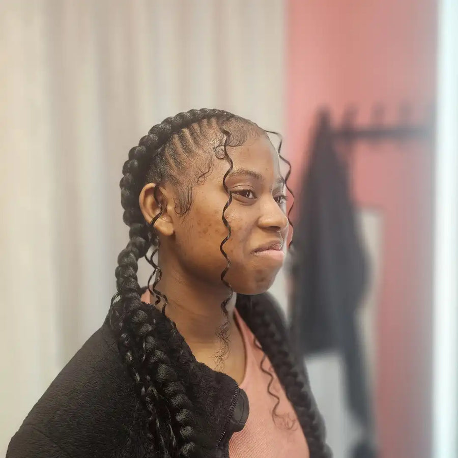 Person with braided hair looking to the side, with a blurred background
