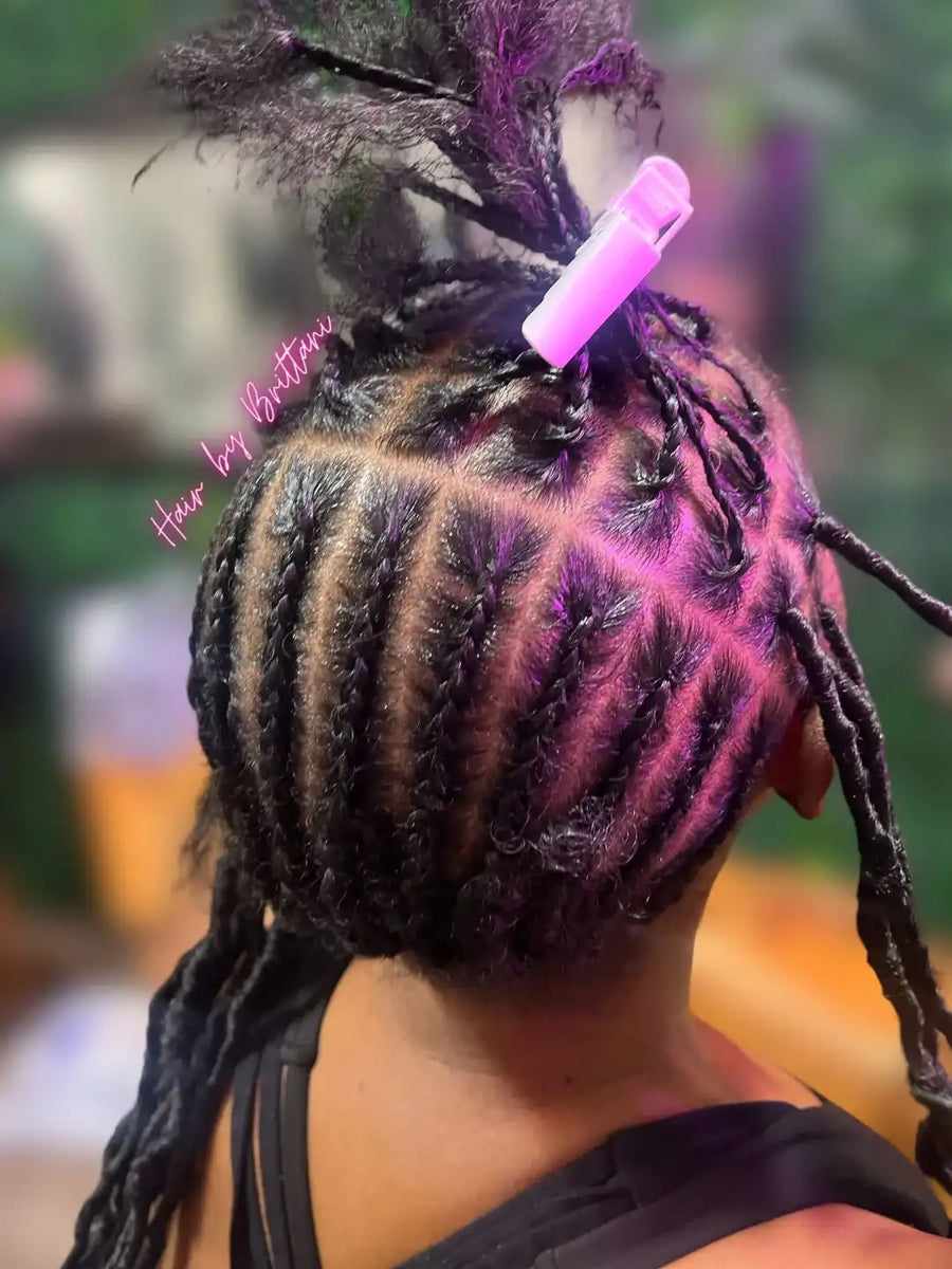 Person with styled hair featuring pink and purple highlights, with 'Hair by Brittany' text.