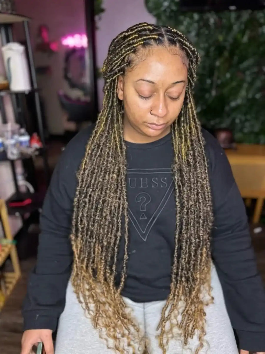 Person with long braided hair wearing a black shirt with a logo in an indoor setting.