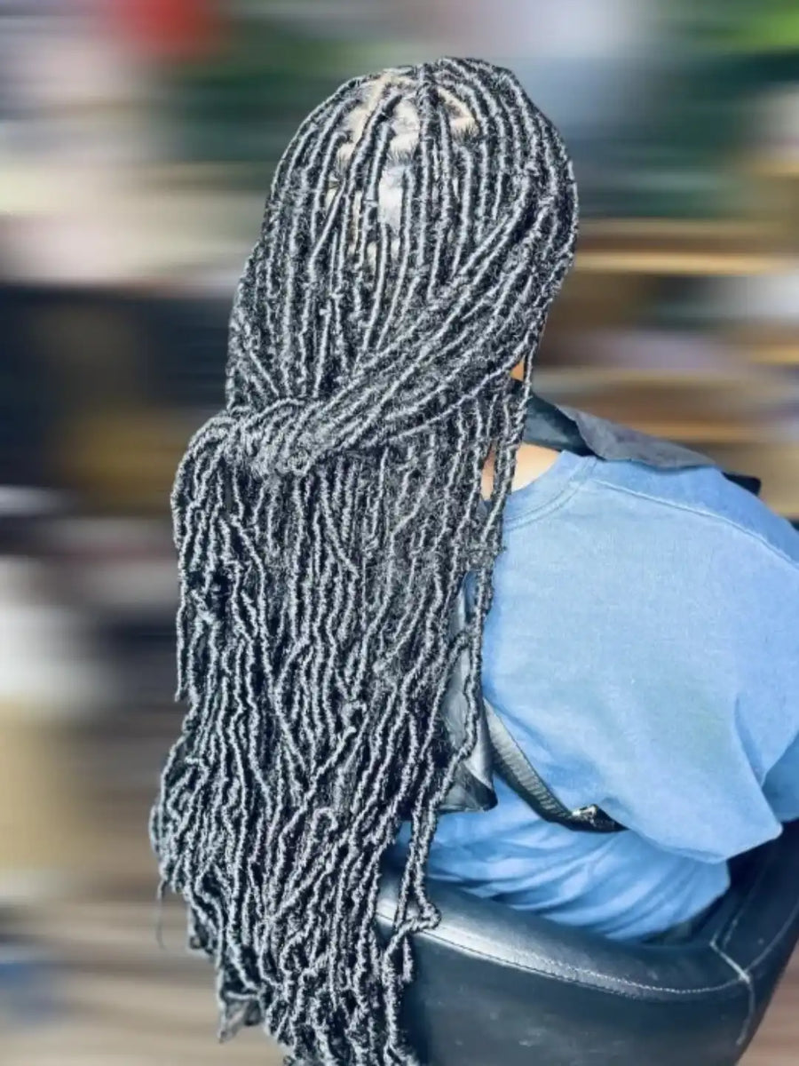 Person with braided hair wearing a blue shirt in an indoor setting