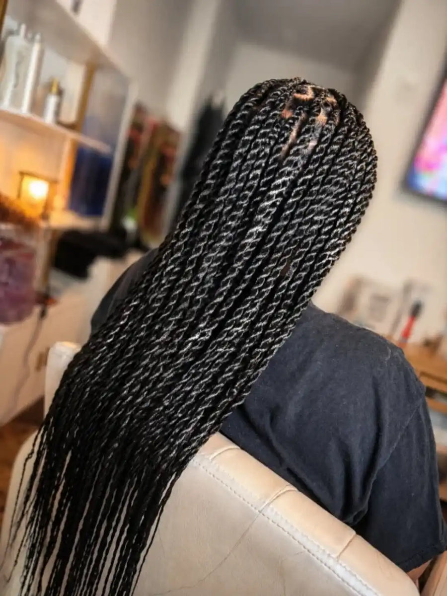 Person with long braided hair in a blurred indoor setting