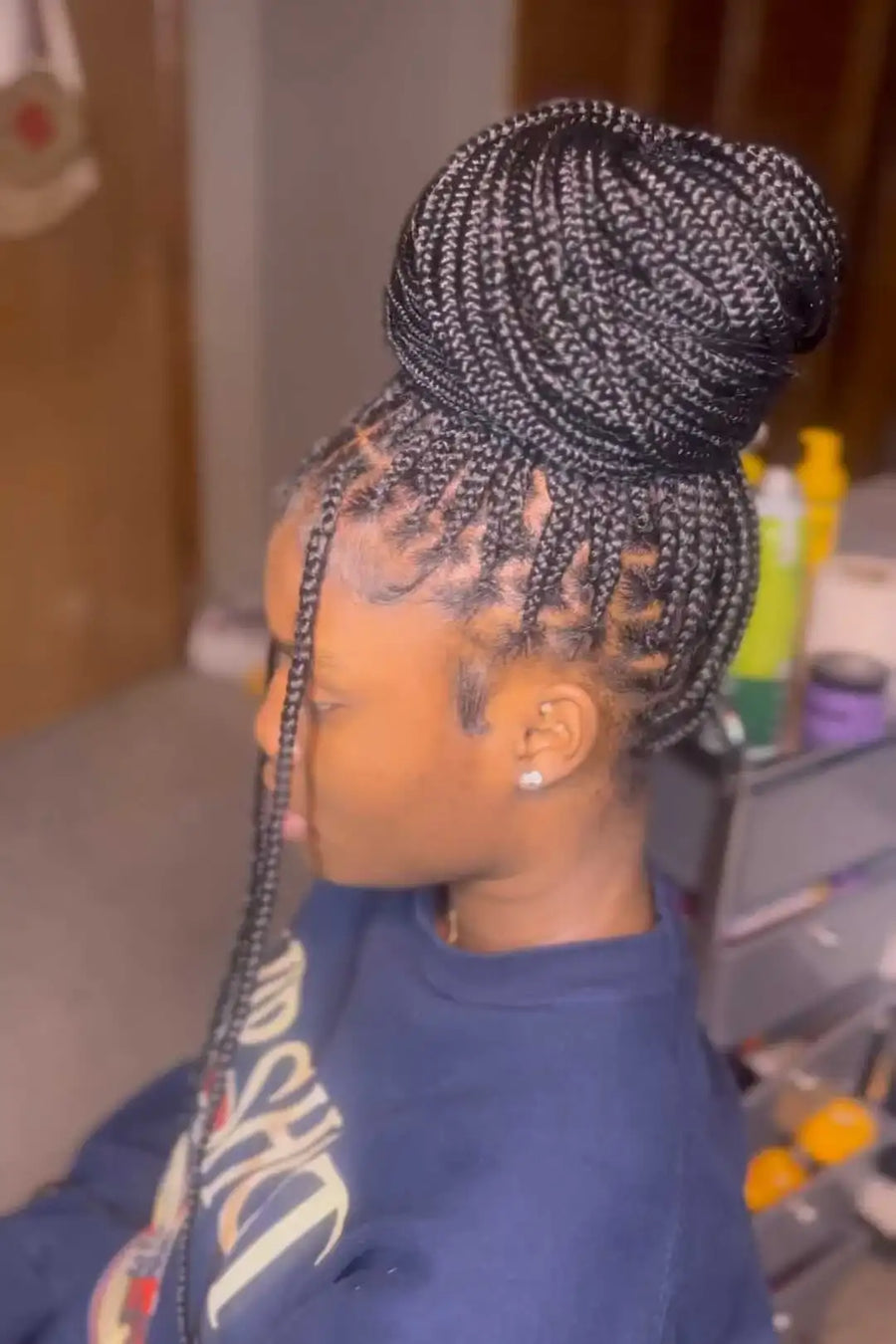 Person with braided hair wearing a blue sweatshirt in an indoor setting