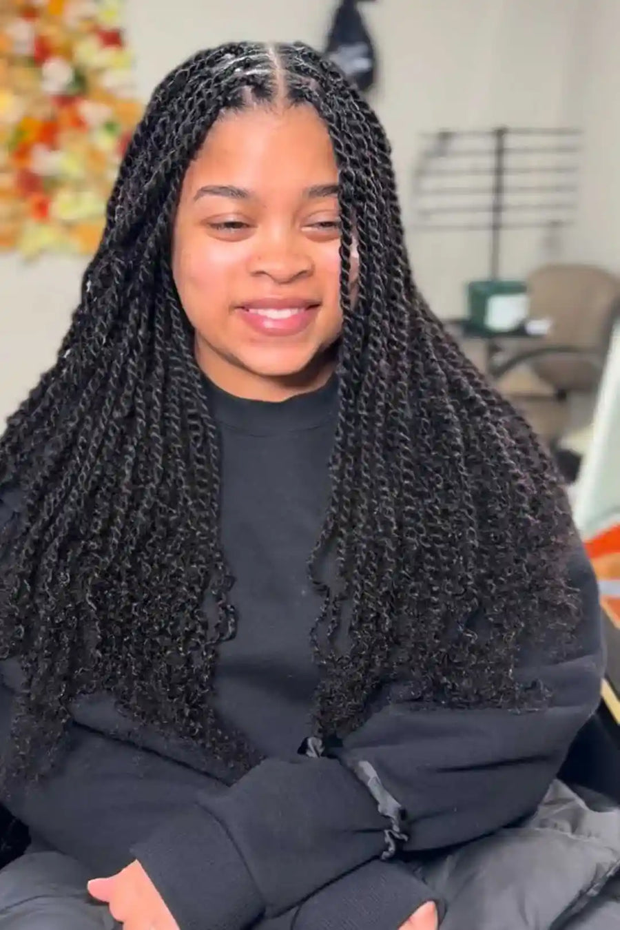 Person with braided hair wearing a black jacket indoors