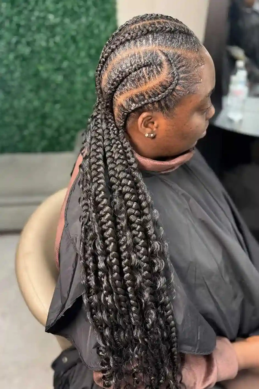 Person with braided hair sitting in a salon chair.