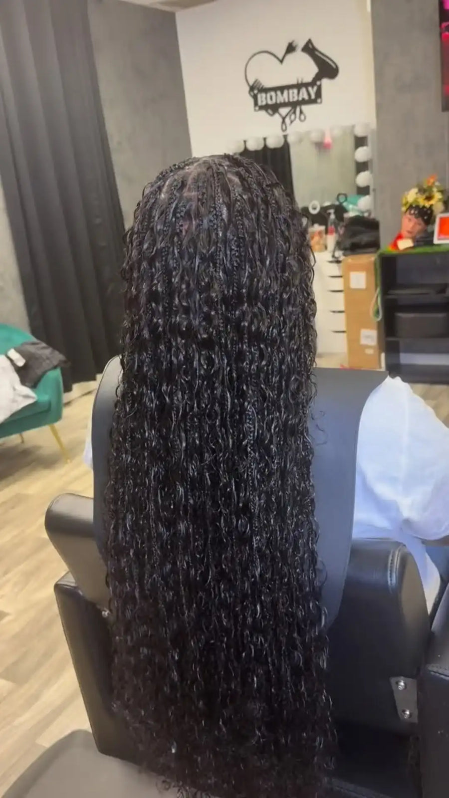 Person with long, textured hair sitting in a salon chair with a salon interior in the background.