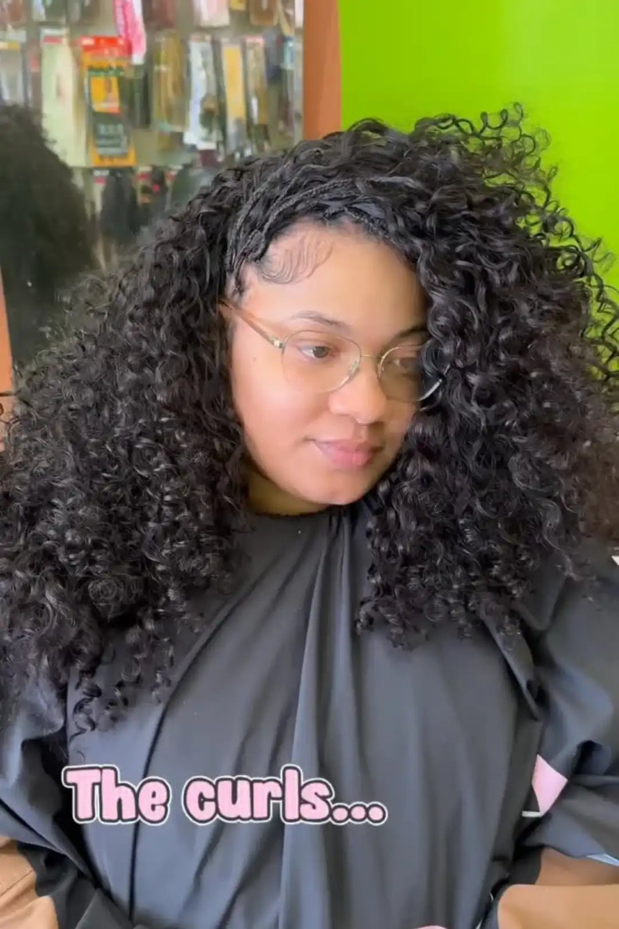 Person with curly hair wearing a salon cape, with text 'The curls...' on a green salon background.