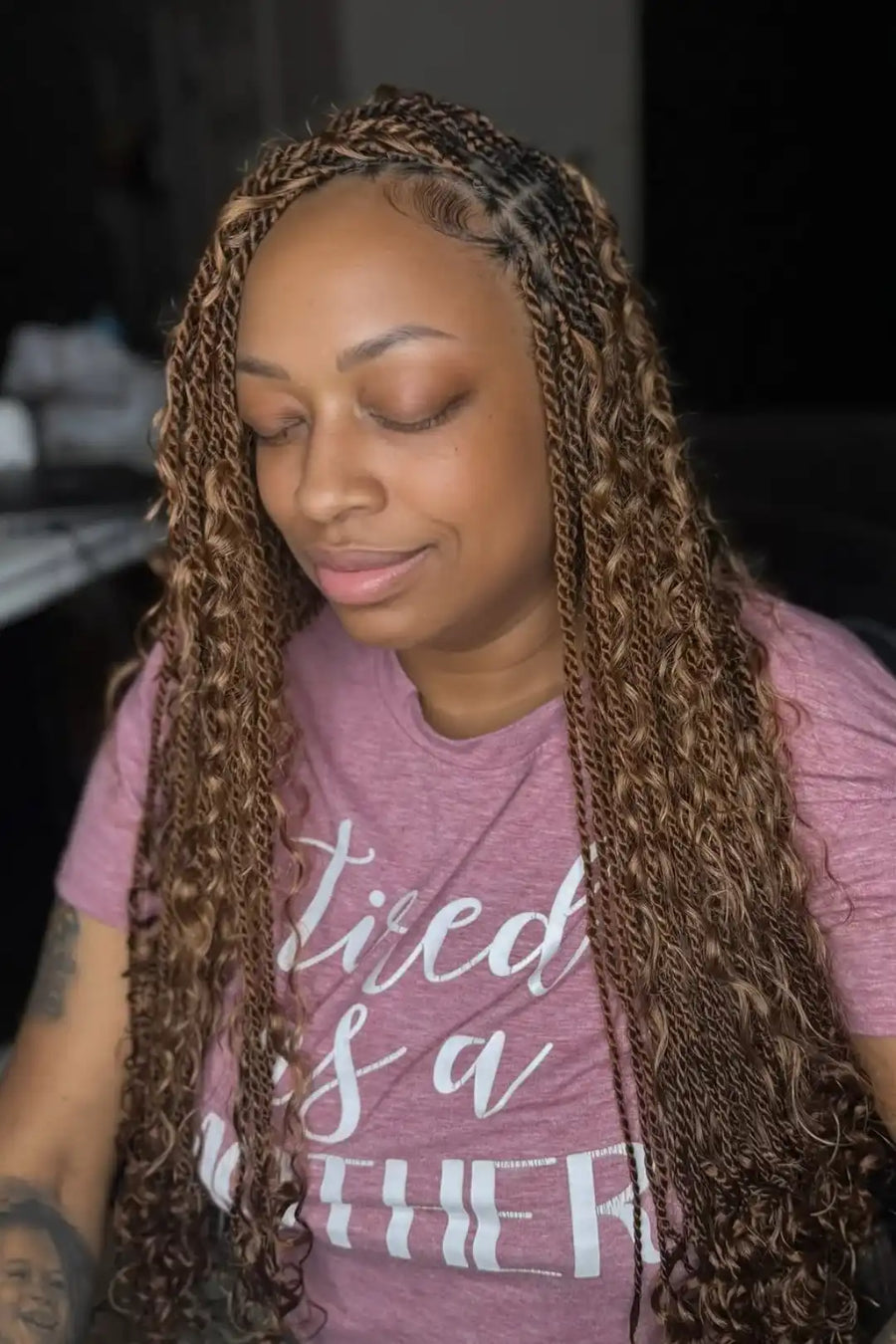 Woman with braided hair wearing a pink t-shirt with text.
