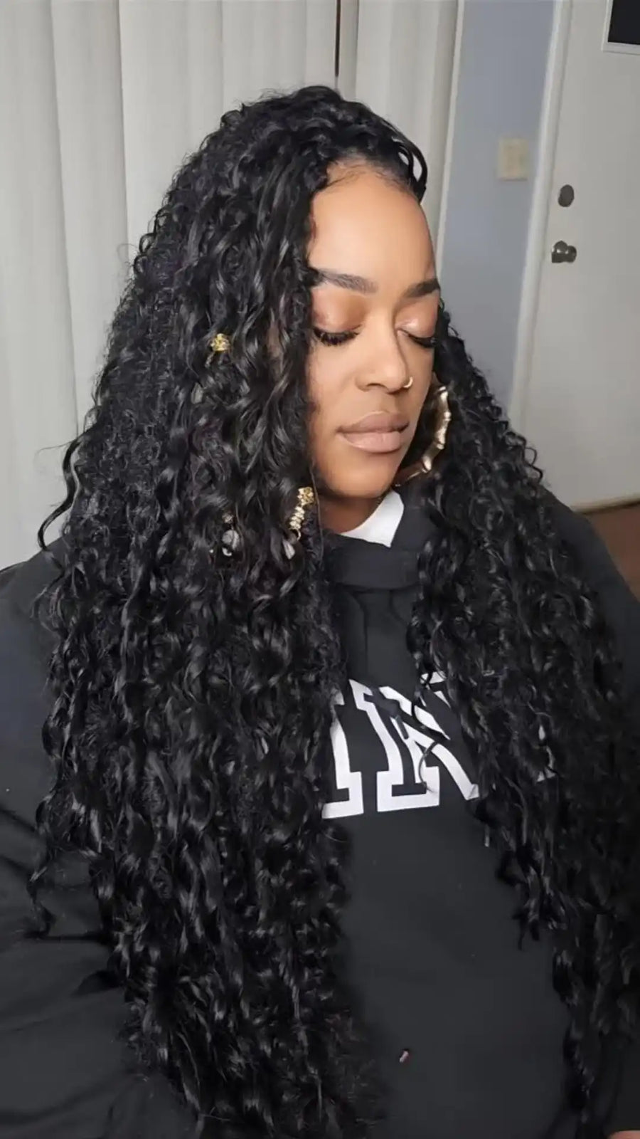 Person with long, styled hair wearing a black top with white text.