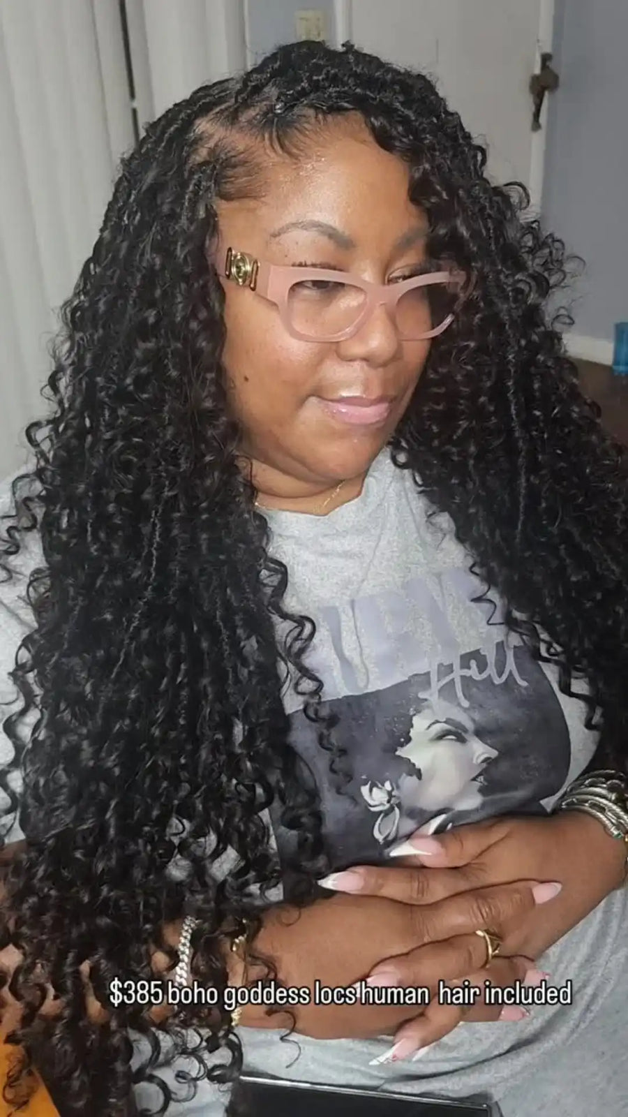 Person with long, curly hair wearing glasses and a gray shirt with a graphic design.