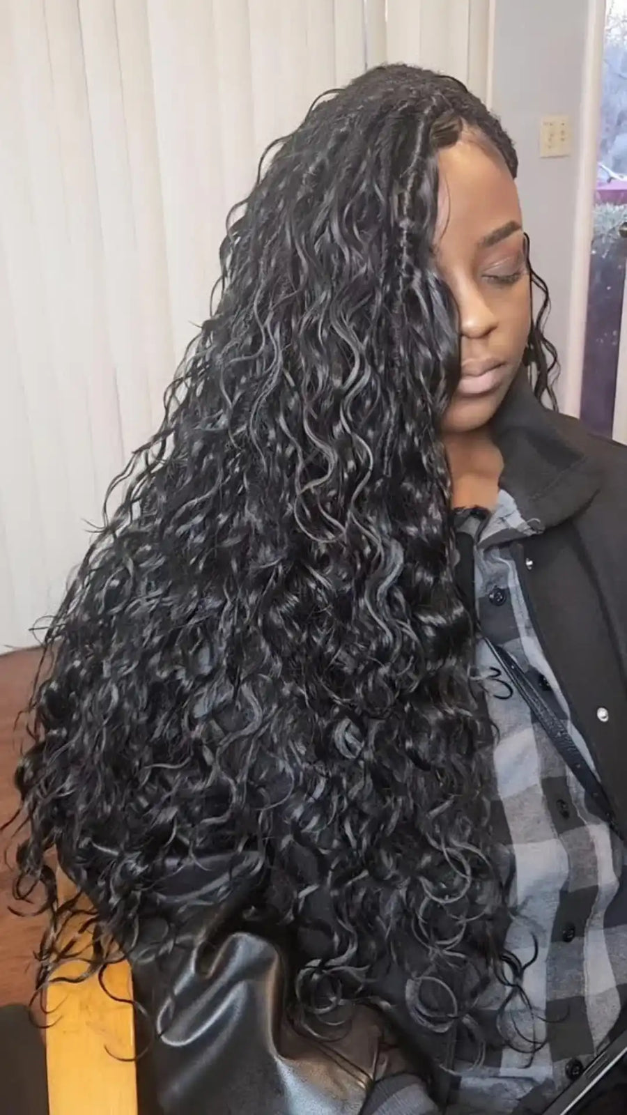 Person with long, curly hair styled in a braid, wearing a black jacket.