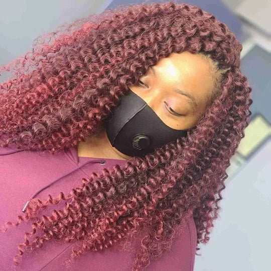Person with maroon hair styled in twists, wearing a black face mask.