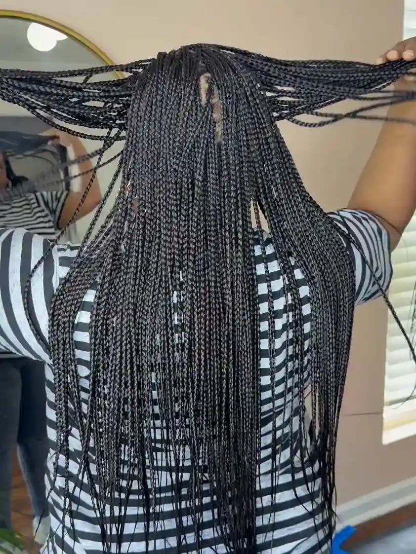 Person holding up a large set of braided hair extensions indoors.