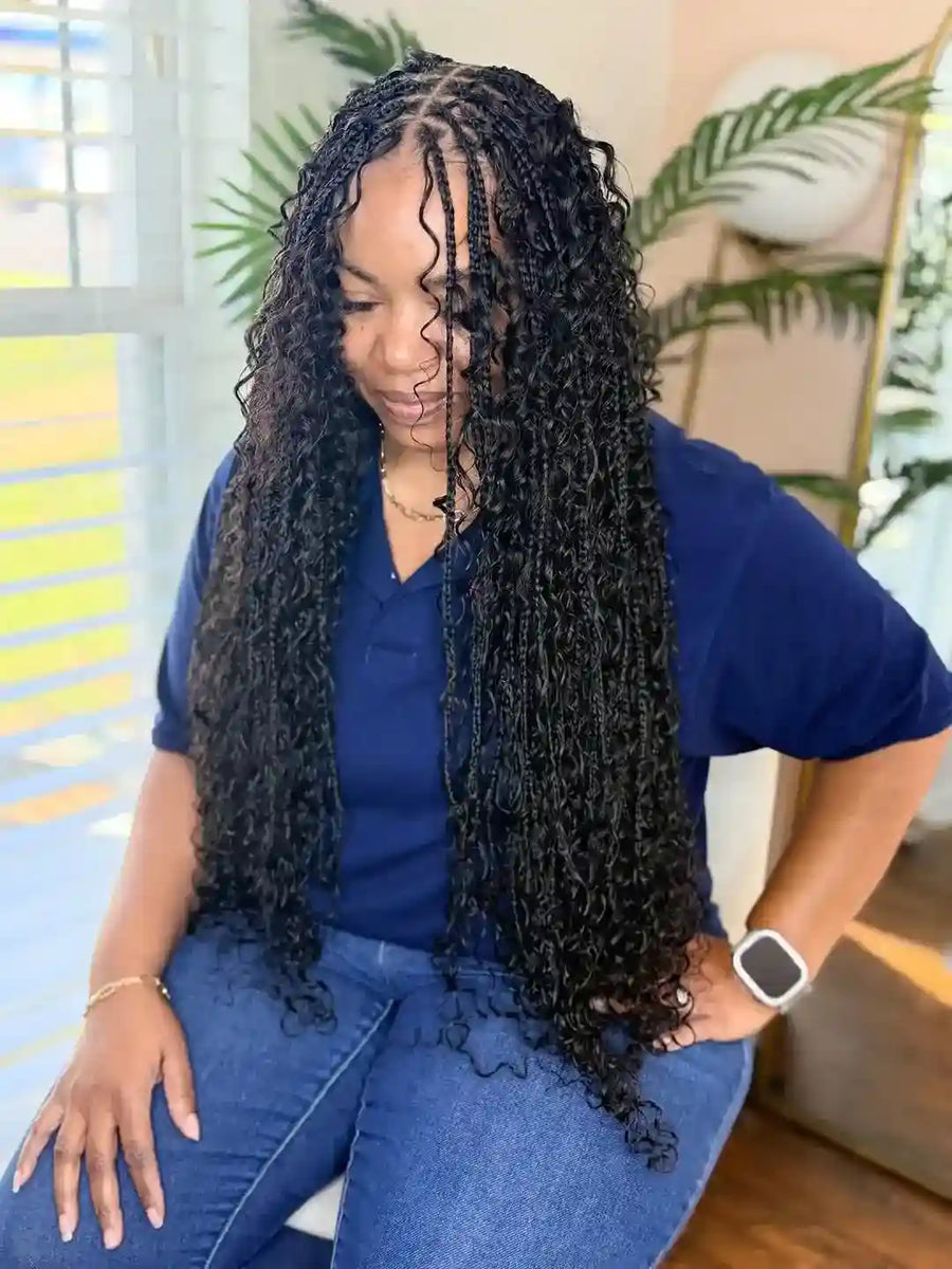 Woman with long braided hair wearing a blue shirt and jeans indoors.