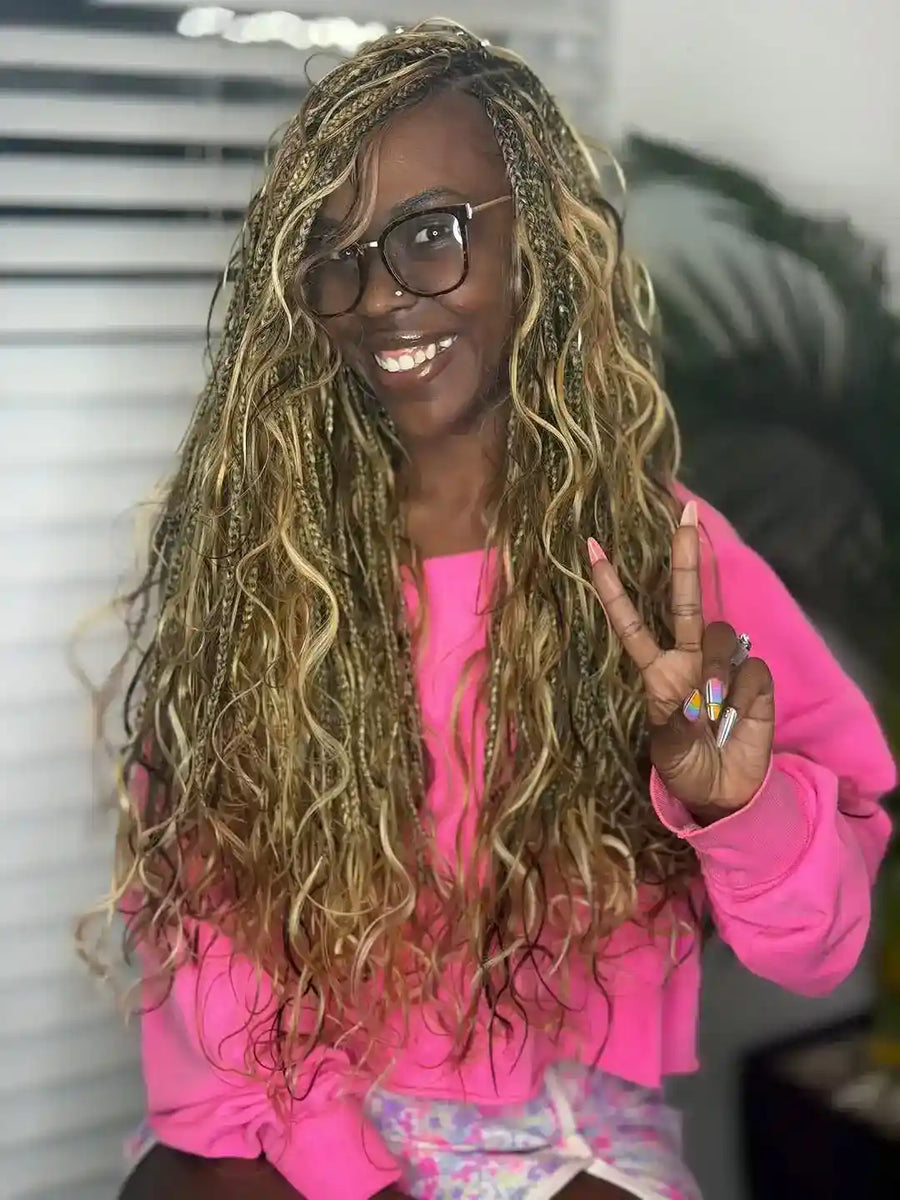 Woman with long, wavy hair wearing glasses and a pink jacket, making a peace sign.