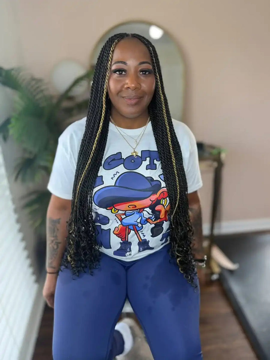 Person wearing a white t-shirt with a colorful graphic design and blue leggings indoors.