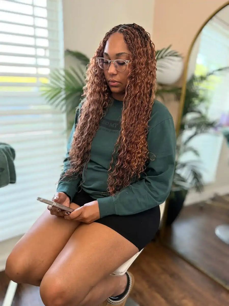 Woman sitting indoors using a phone, wearing glasses and a green top.
