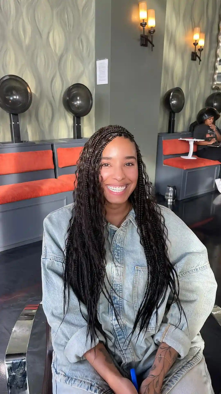 Woman with braided hair wearing a denim jacket in a restaurant setting