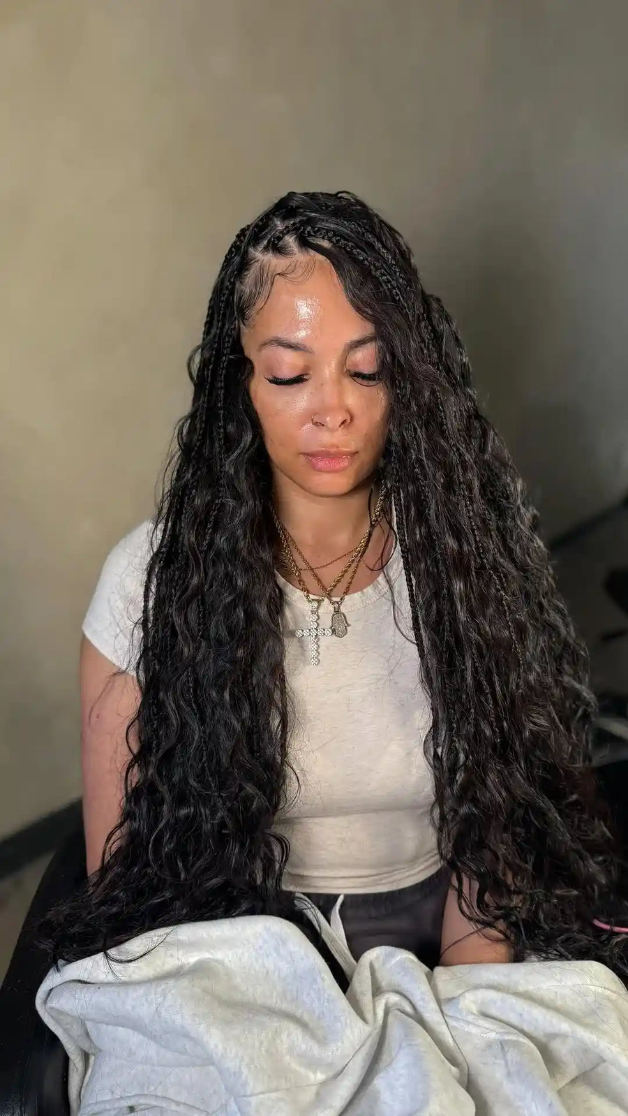 Woman with long braided hair sitting on a couch wearing a white shirt.