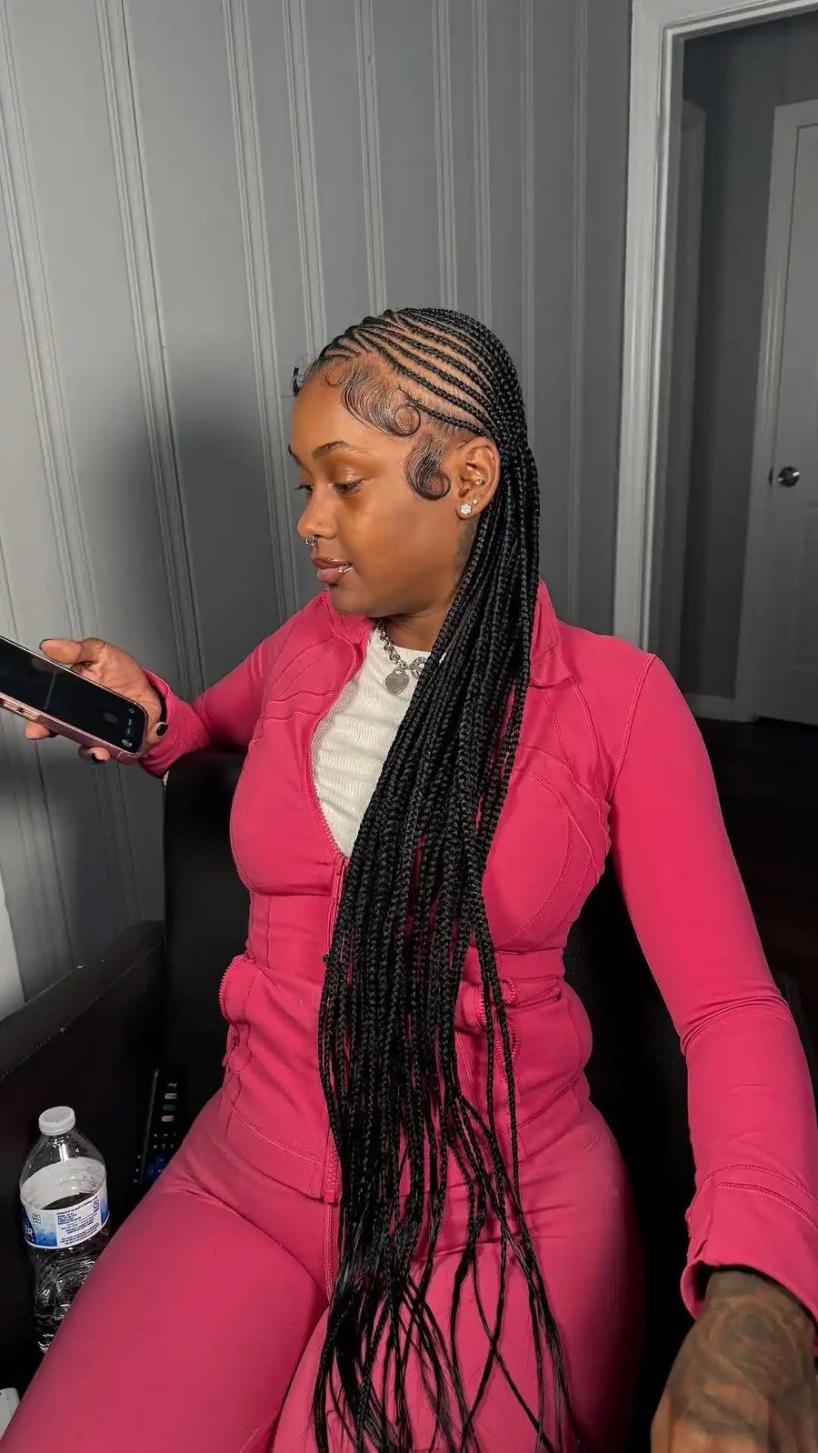Person in a pink outfit sitting on a couch holding a phone.