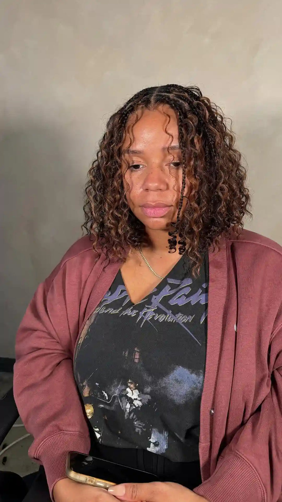 Woman wearing a maroon sweatshirt over a black graphic t-shirt with text and graphics.