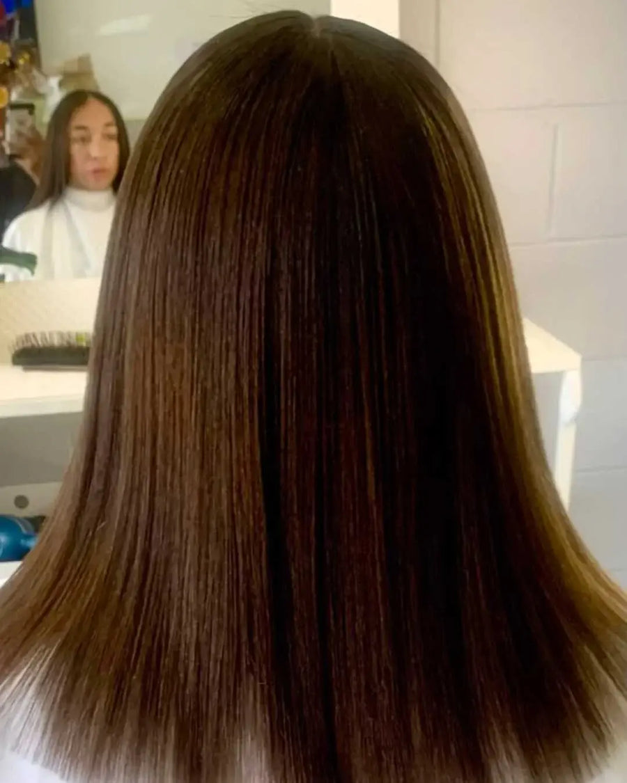 Close-up of a person with long, straight brown hair in a bathroom setting.