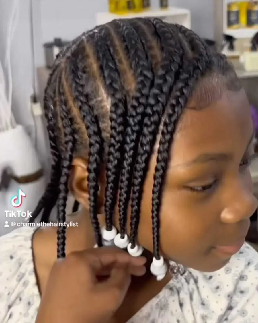 Child with braided hair being styled in a salon setting