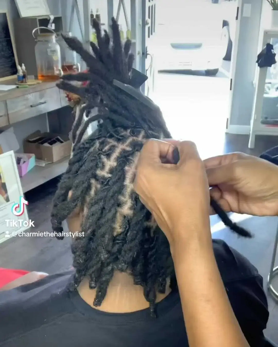 Person styling dreadlocks in a salon setting