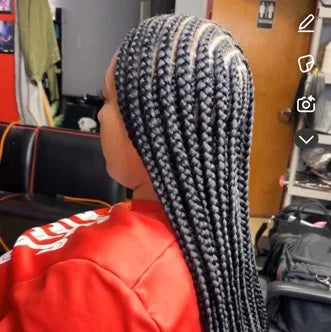 Person with braided hair wearing a red hoodie in a room with furniture and equipment.