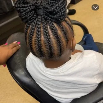 Person with braided hair sitting in a chair, receiving a haircut.