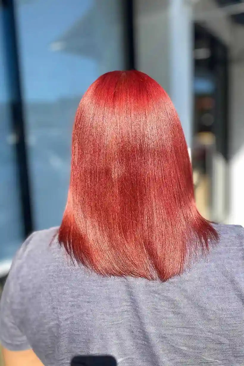 Person with red hair wearing a gray shirt outdoors