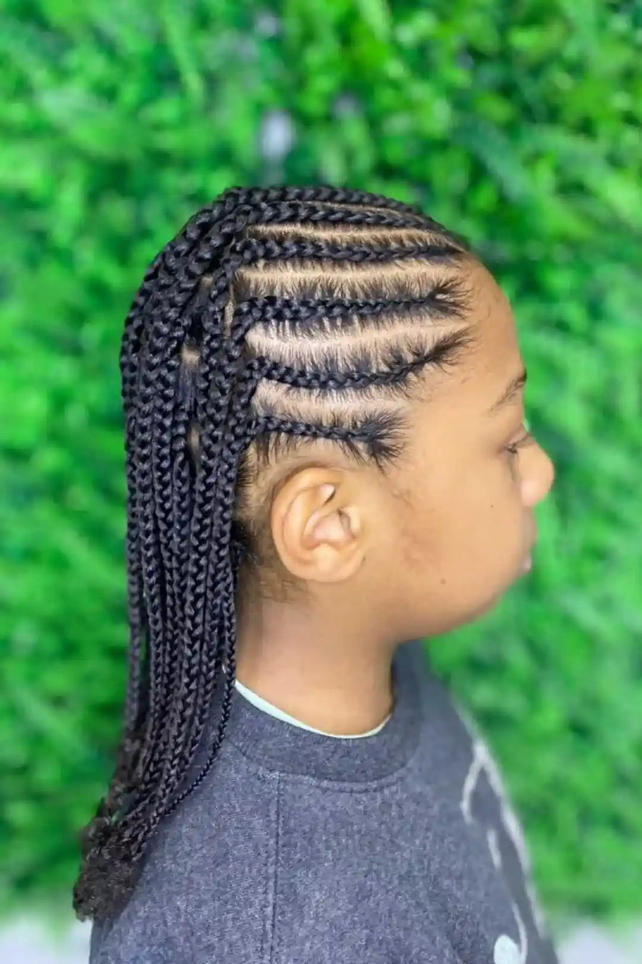 Person with braided hair in front of a green outdoor background
