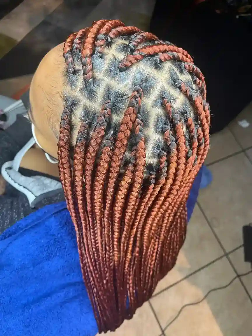 Person with braided hair styled in cornrows on a tiled floor background