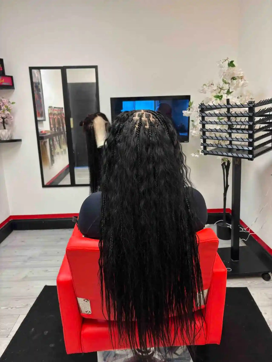 Person with long black hair sitting in a salon chair, facing a computer screen.