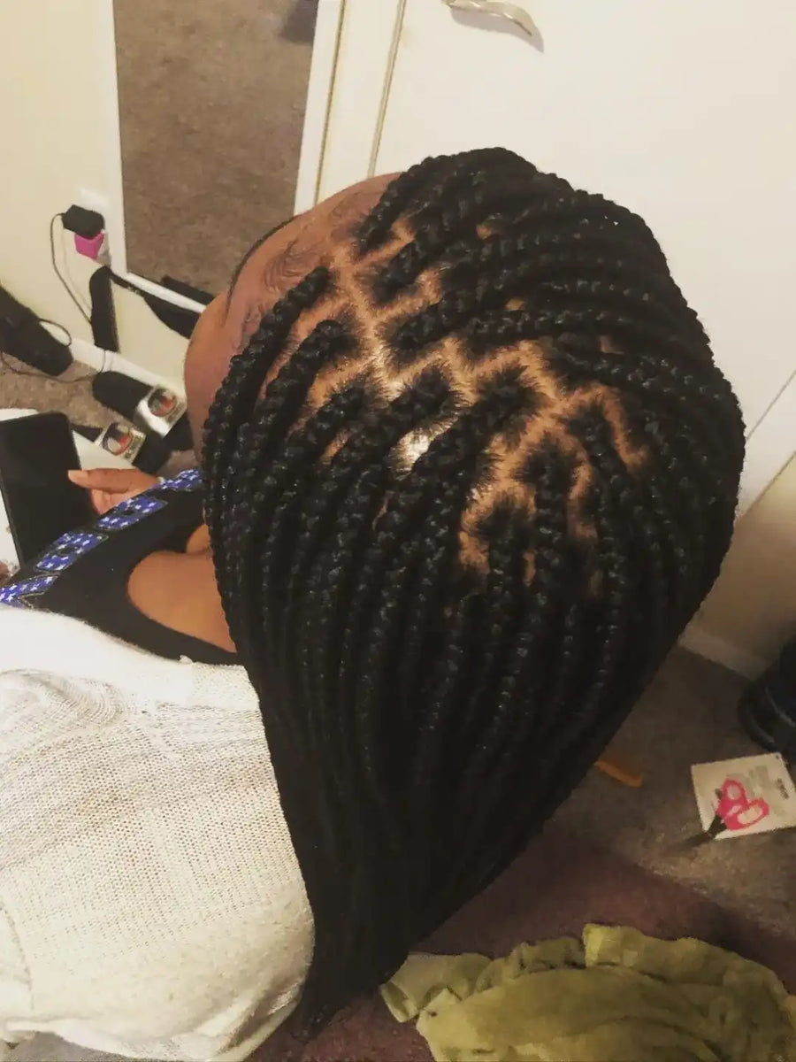 Person with braided hair sitting on a couch in a casual setting