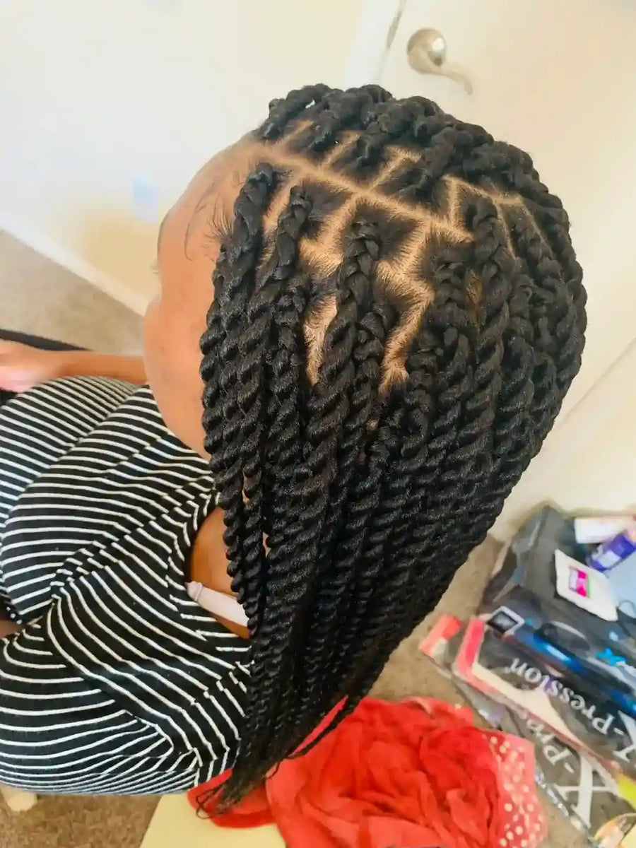 Person with braided hair sitting on a chair in a room.