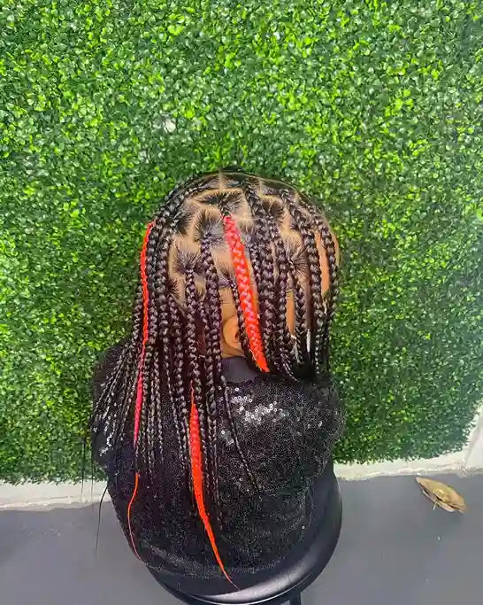 Black mannequin head with braided hair featuring red accents against a green textured wall.