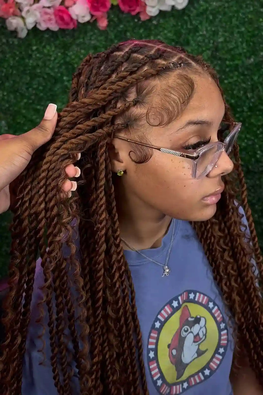 Person with braided hair wearing glasses and a blue shirt with a cartoon character design.