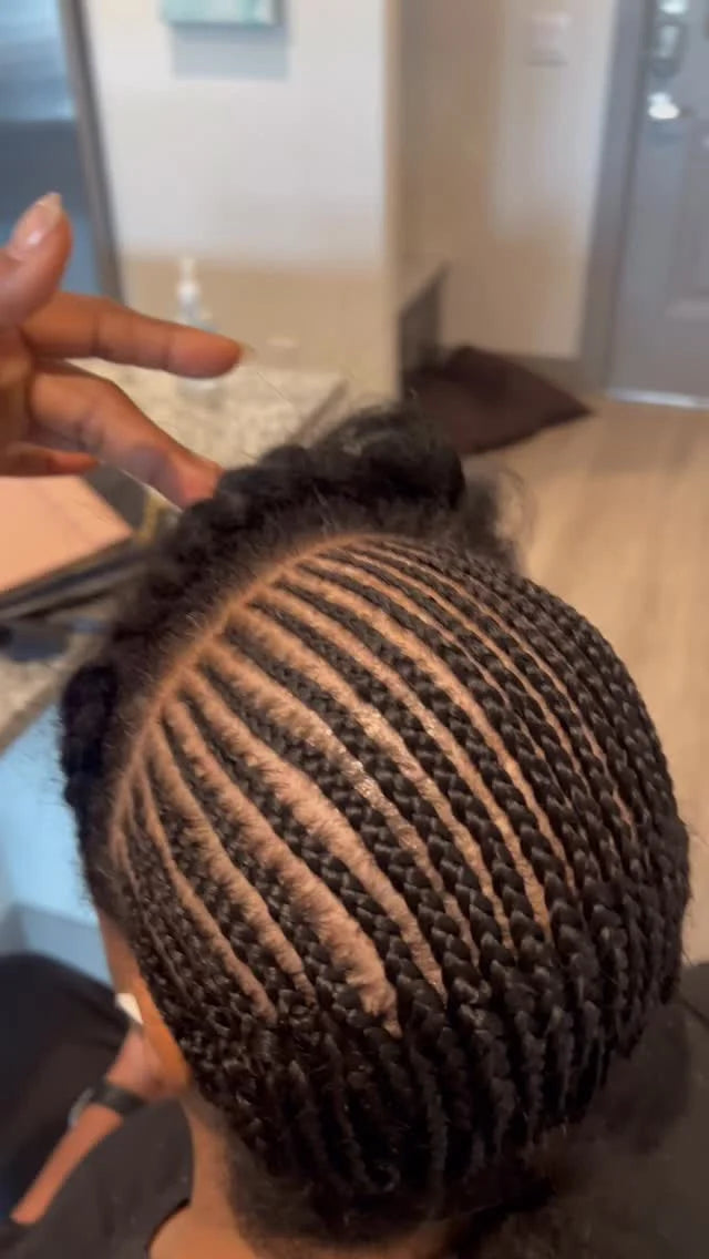 Person with braided hair styled in a bun, indoors.