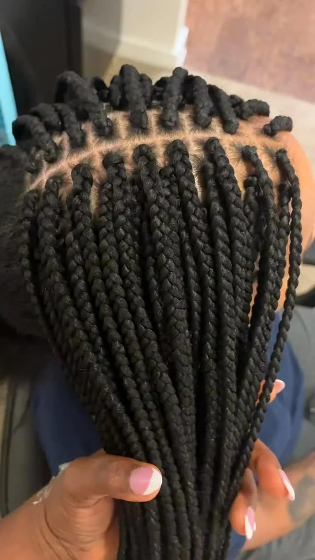 Braided hair extensions held by a person with a blurred background
