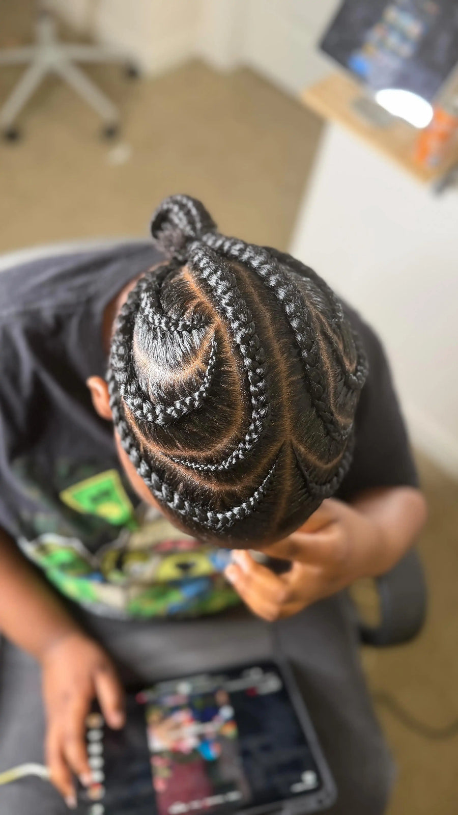 Person with braided hair sitting on a couch holding a tablet.