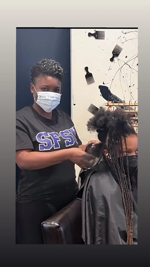 Person getting a haircut in a salon with another person wearing a face mask.