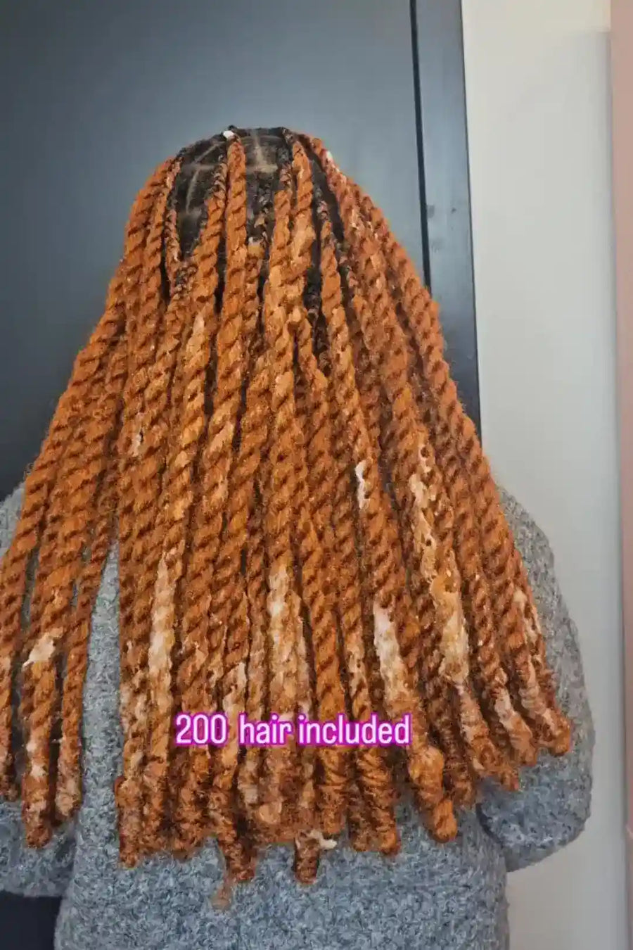 Person with long braided hair extensions on a plain background